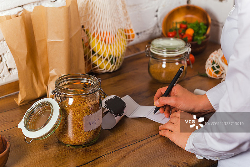 在桌旁纸上书写的女子腰部特写图片素材