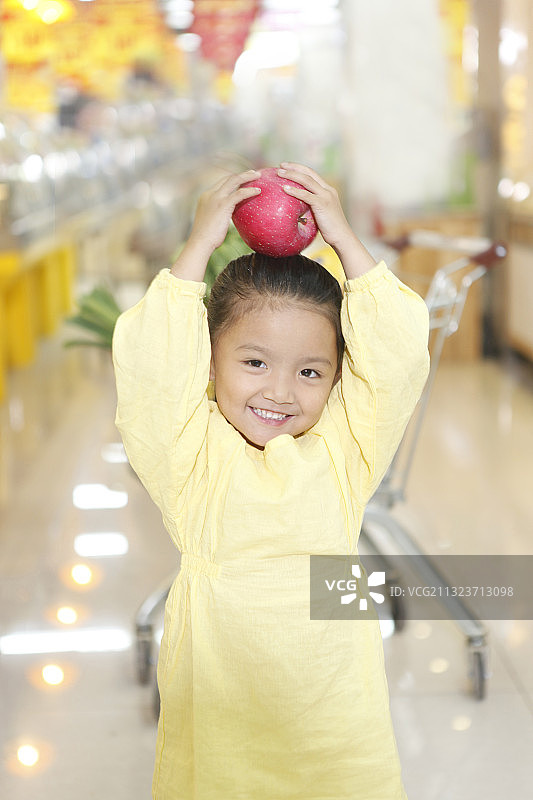 在超市里拿着苹果的可爱女孩图片素材