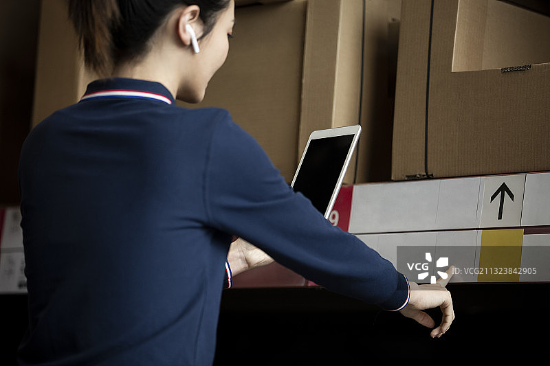 青年女子使用平板电脑在物流仓库帮助顾客展示产品图片素材