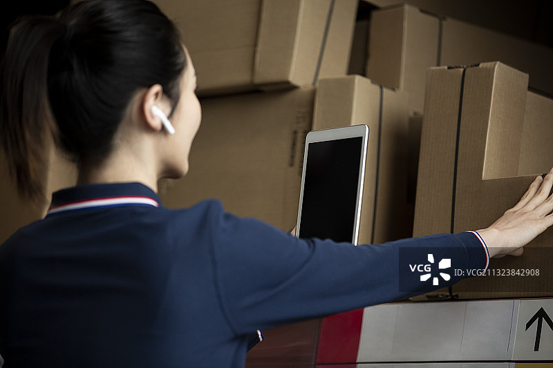 青年女子使用平板电脑在物流仓库帮助顾客展示产品图片素材