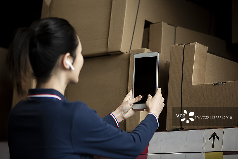 青年女子使用平板电脑在物流仓库帮助顾客展示产品图片素材