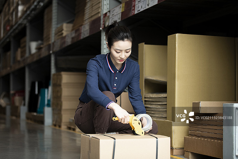青年女子在物流仓库打包封箱工作肖像图片素材