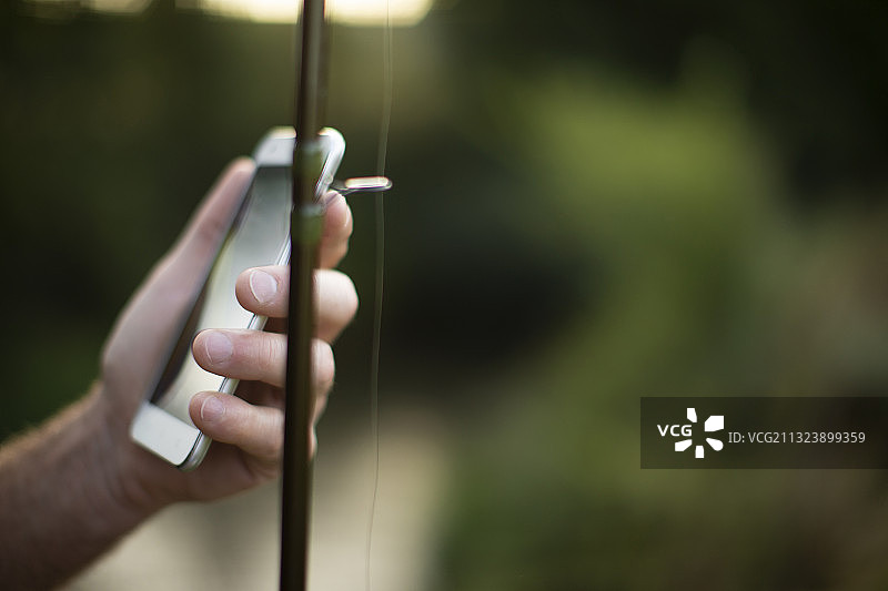 特写：手持智能手机和鱼竿图片素材