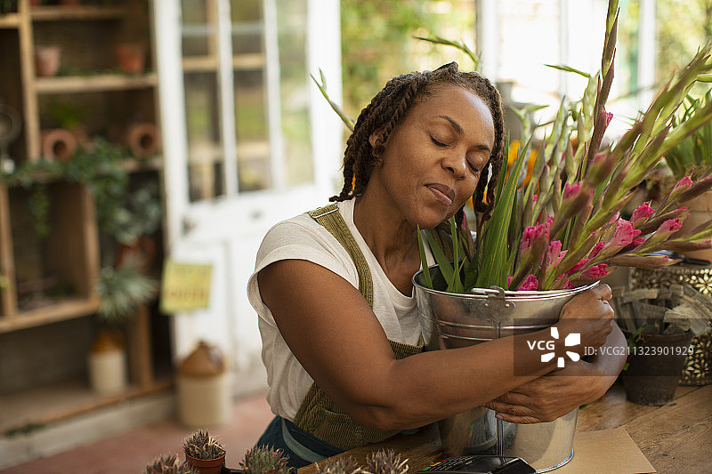 花店里拥抱鲜花桶的宁静女人图片素材