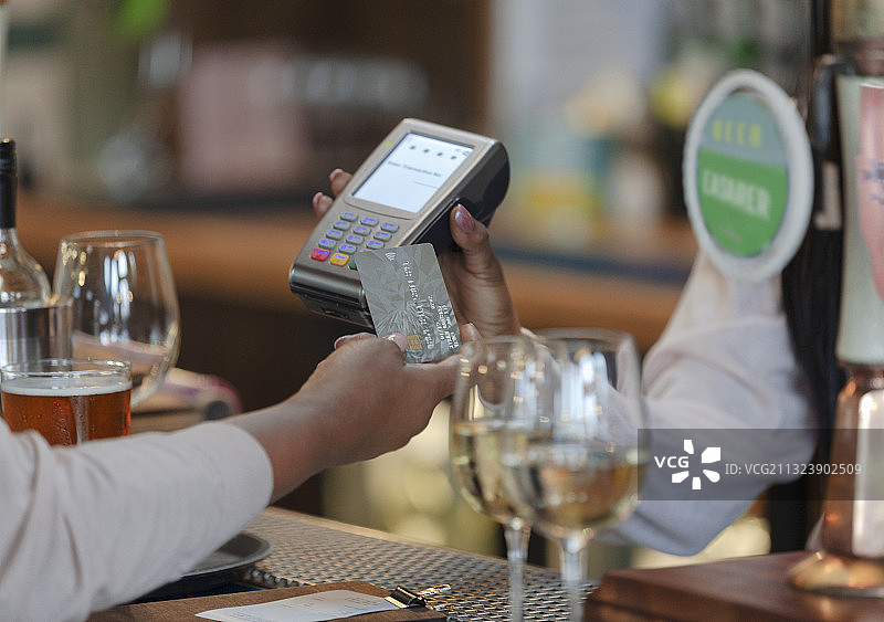 顾客在酒吧用智能卡支付酒保的特写图片素材