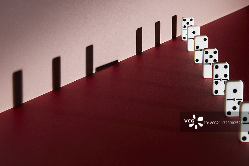 红色背景上的多米诺骨牌和阴影，保持社交距离图片素材