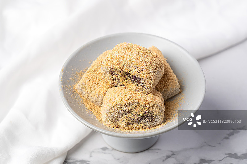 浅色纯色背景上盘子里的北京传统特色糕点小吃驴打滚图片素材