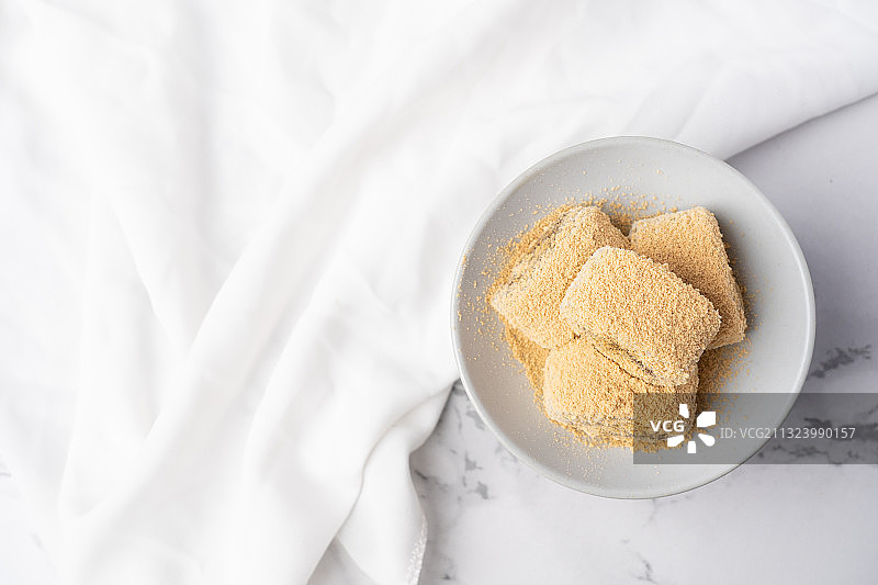 浅色纯色背景上盘子里的北京传统特色糕点小吃驴打滚图片素材