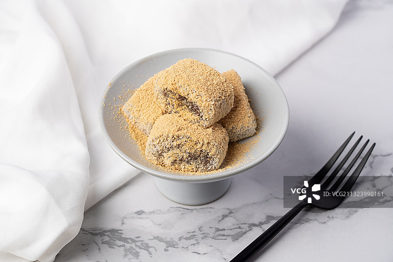 浅色纯色背景上盘子里的北京传统特色糕点小吃驴打滚图片素材