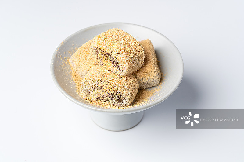 浅色纯色背景上盘子里的北京传统特色糕点小吃驴打滚图片素材