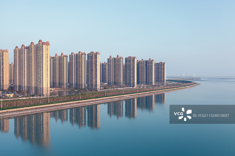 清晨阳光下的高层居民建筑在海面上投下倒影图片素材