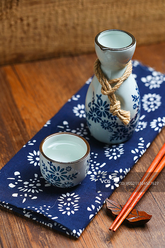 日本清酒白酒酒壶酒杯酒具放在蓝花布上图片素材