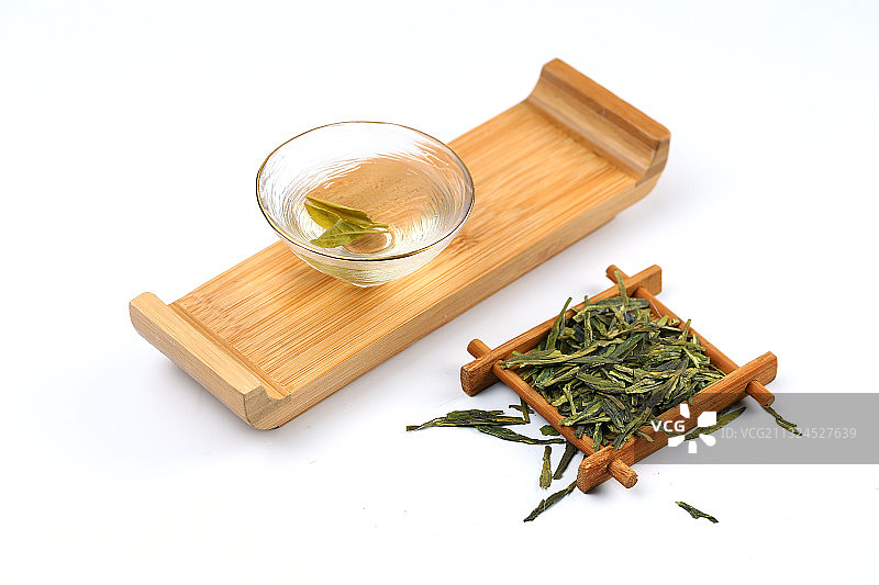 玻璃茶杯斗笠杯里的西湖龙井茶和茶叶放在白色背景上图片素材