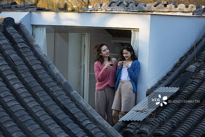 两个闺蜜在户外阳台喝咖啡闲谈看风景图片素材
