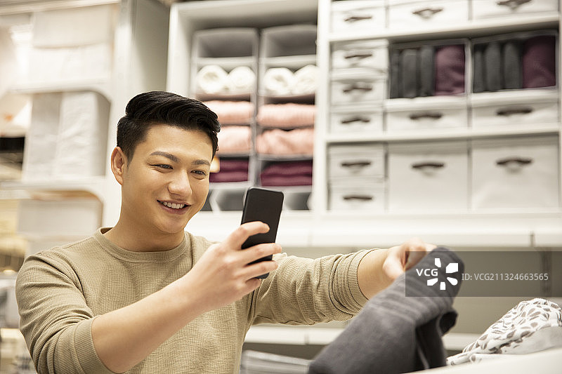 青年男子在家居商店使用手机视频购物图片素材