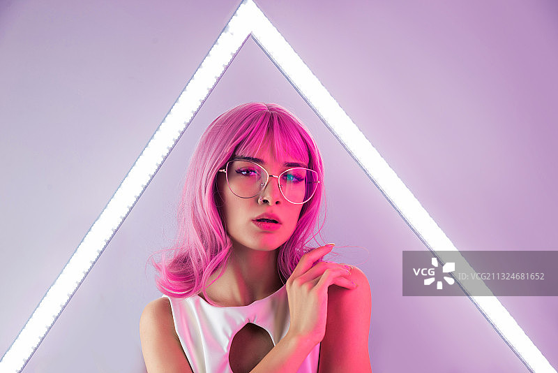 年轻女性站在灯光墙前的彩色艺术肖像图片素材