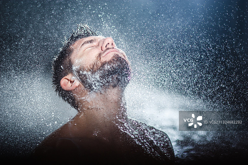 闭着眼睛用水管泼水的年轻男子图片素材