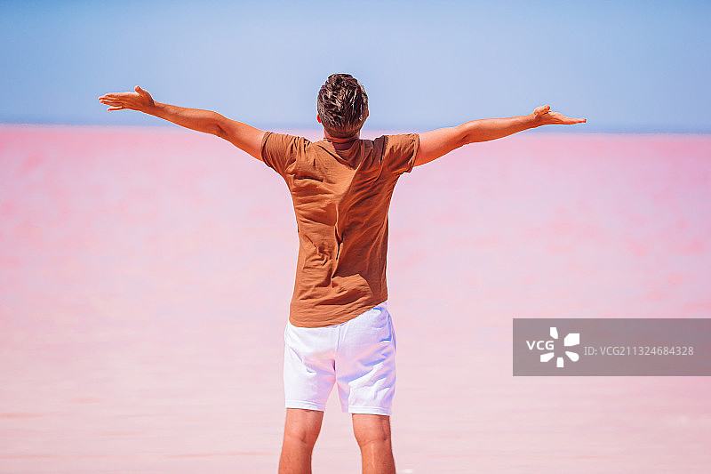 男子张开双臂眺望粉色大海的背影图片素材