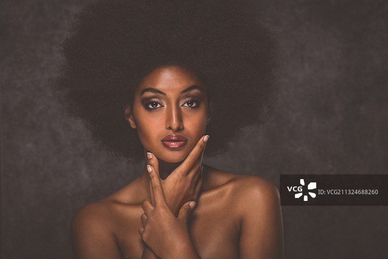 裸露上身的年轻女子肖像，手托下巴，灰色背景图片素材