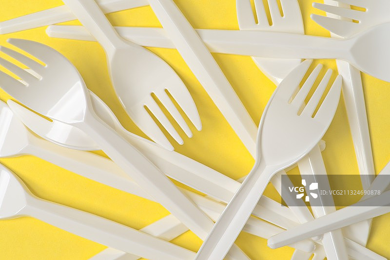 黄色背景上桌子上的塑料勺子和叉子俯视图图片素材