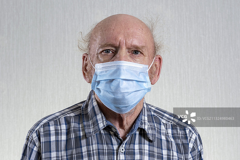 戴外科口罩的男人靠在墙上的肖像图片素材