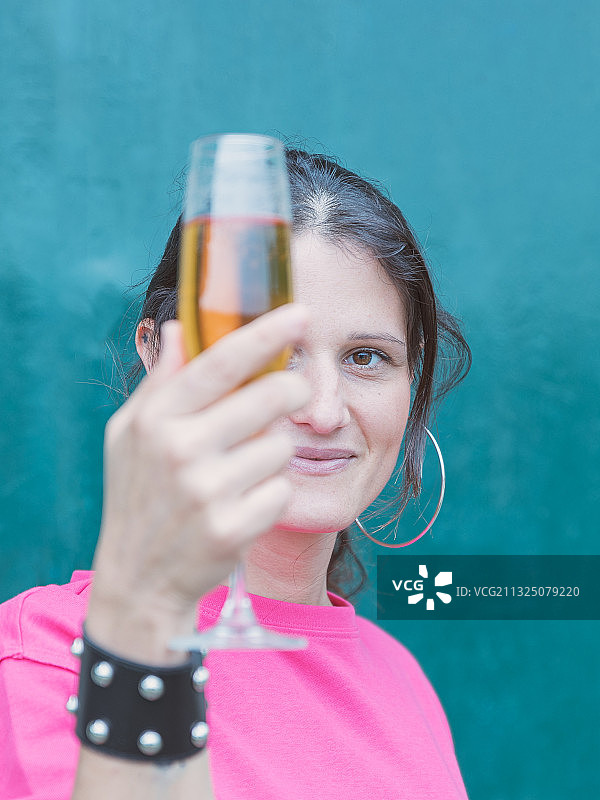 微笑的年轻女性拿着饮料靠在墙上的肖像，意大利图片素材