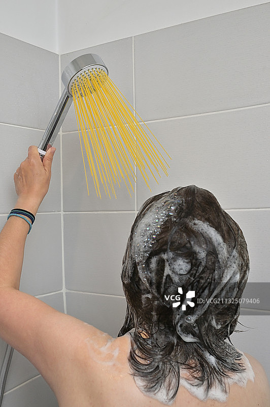 站在淋浴下，长长的意大利面像水柱一样的女孩图片素材