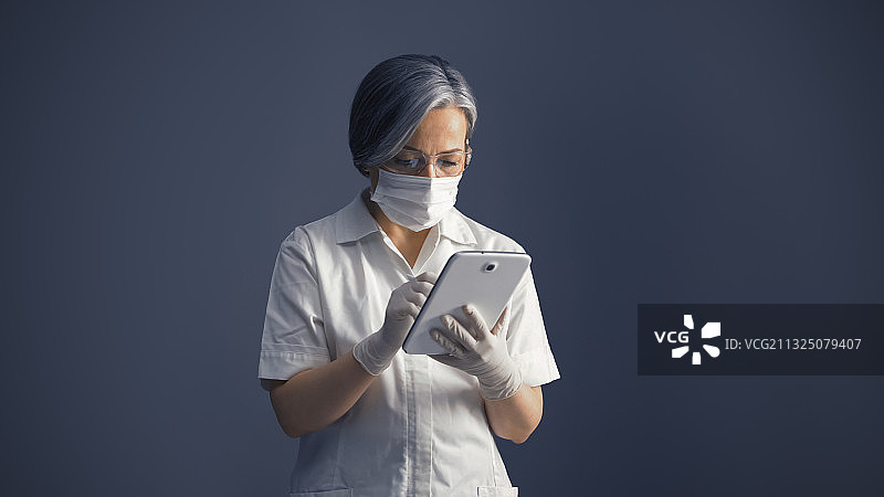 女医生在灰色背景前使用平板电脑图片素材