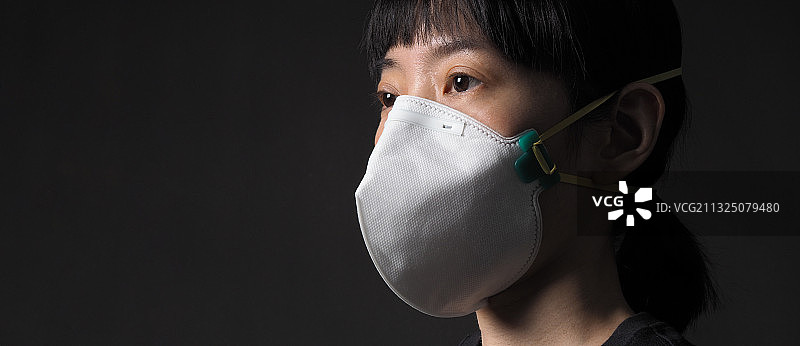 戴防护口罩的女人特写镜头，背景为黑色，泰国曼谷图片素材