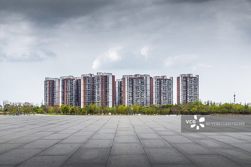 从平坦干净的城市广场看向远处的城市高层住宅楼图片素材