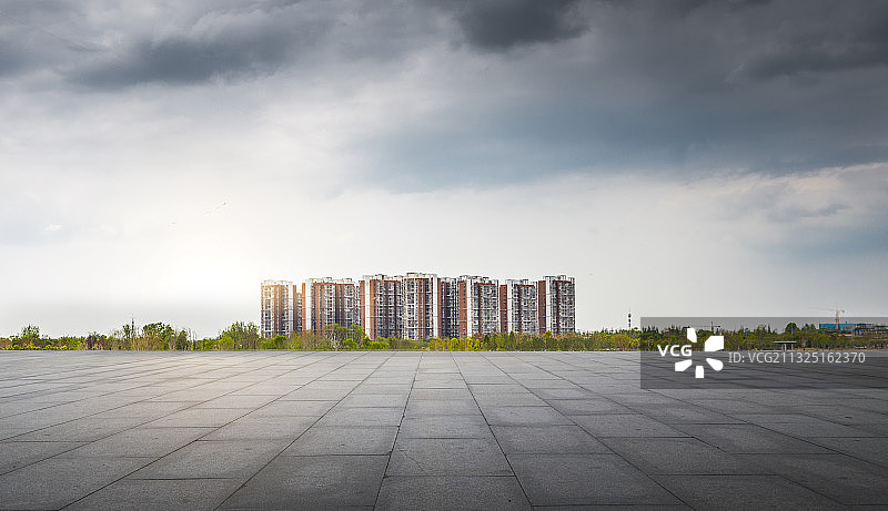 从平坦干净的城市广场看向远处的城市高层住宅楼图片素材