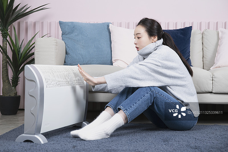 亚洲单身女性独自一人在冬天使用电暖器图片素材