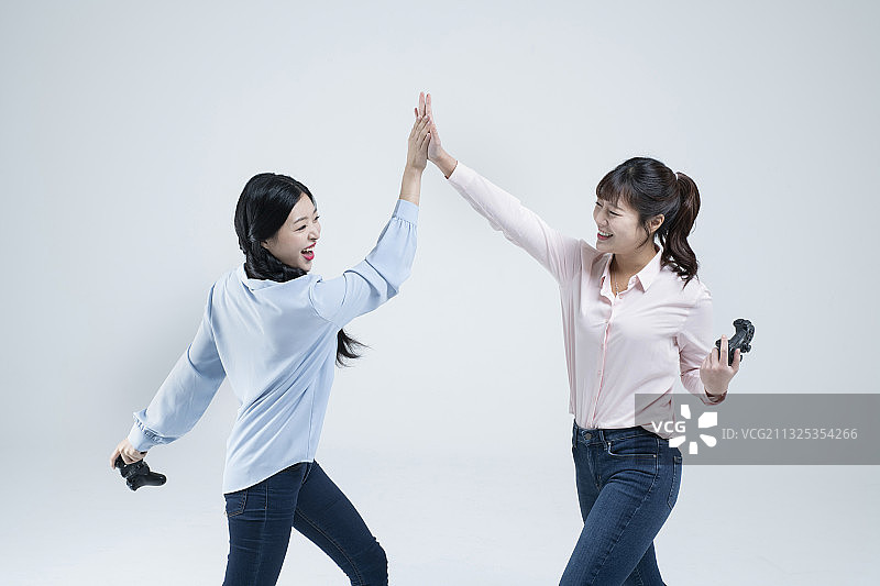 两位亚洲姐妹用游戏手柄玩电子游戏图片素材