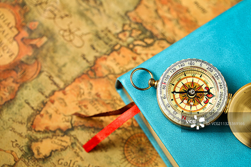 指南针和复古书本放在复古地图背景上图片素材