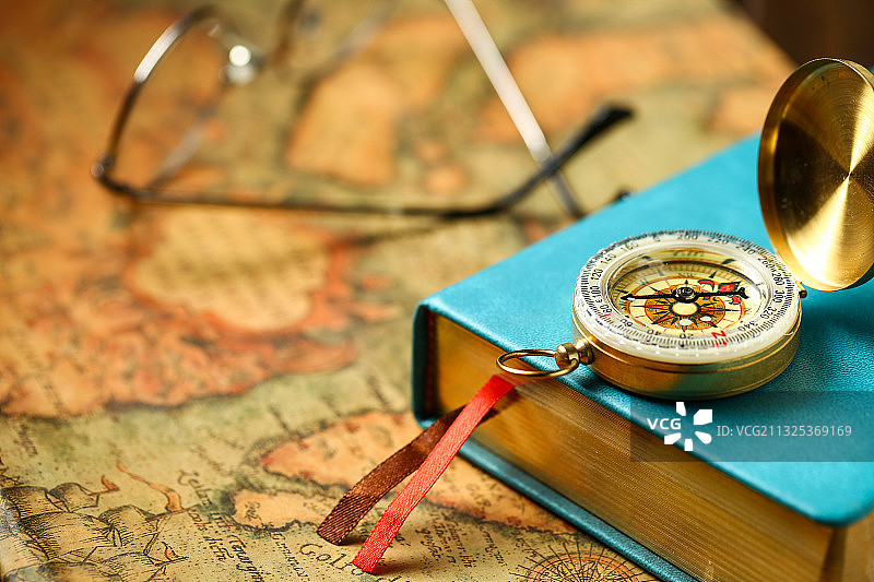 指南针和复古书本放在复古地图背景上图片素材