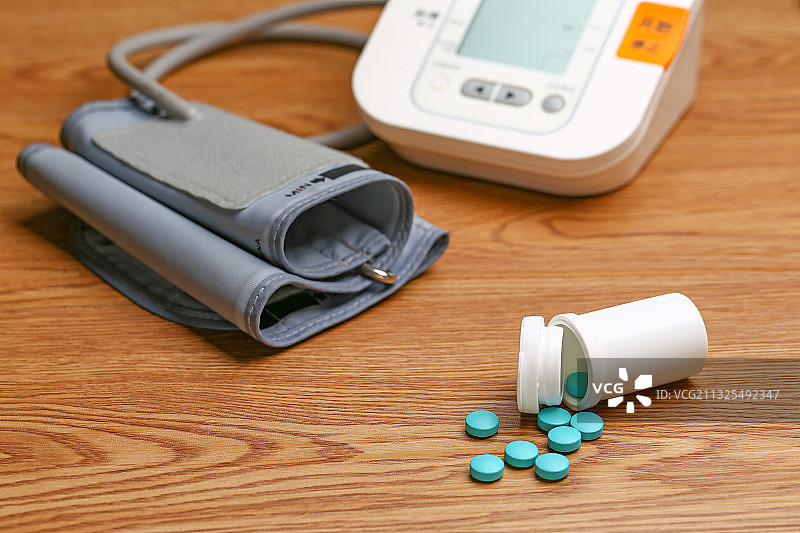 电子血压计和药瓶放在木桌上图片素材