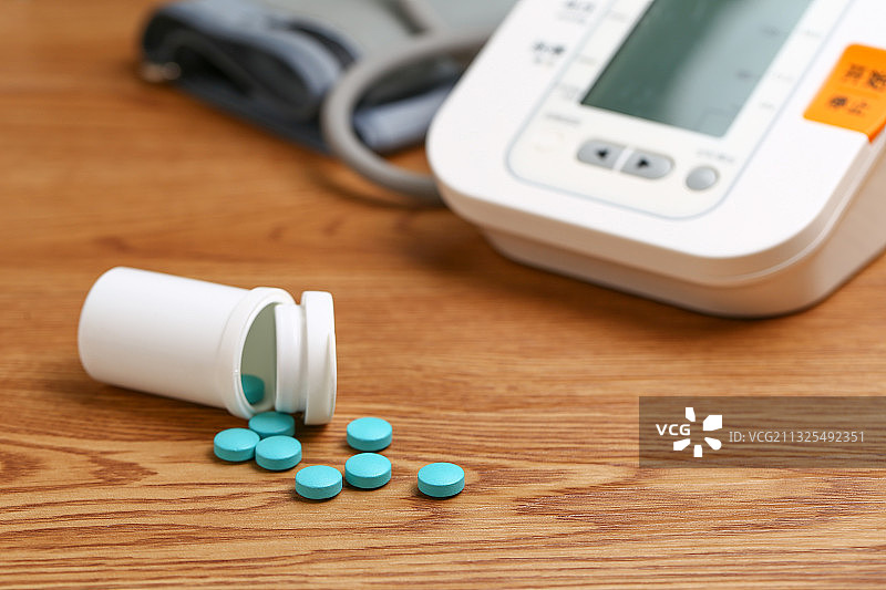 电子血压计和药瓶放在木桌上图片素材