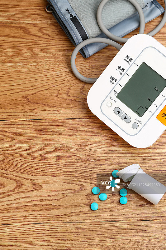 电子血压计和药瓶放在木桌上图片素材