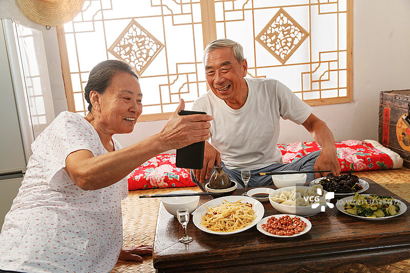 老年夫妇在家里吃饭看手机图片素材
