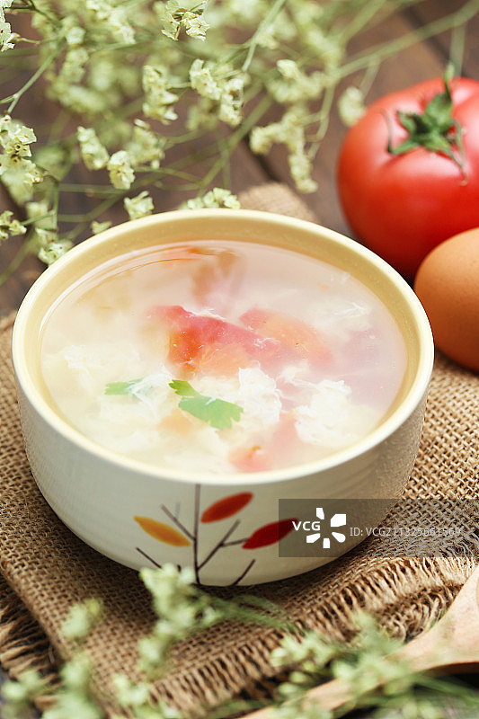 西红柿鸡蛋汤和木勺放在粗麻布背景上图片素材