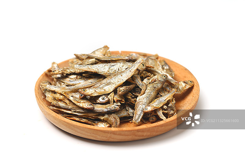 小鱼干放在木盘里在纯白色背景上图片素材