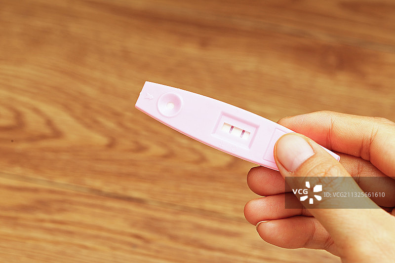 拿着显示怀孕的验孕棒的女性手图片素材