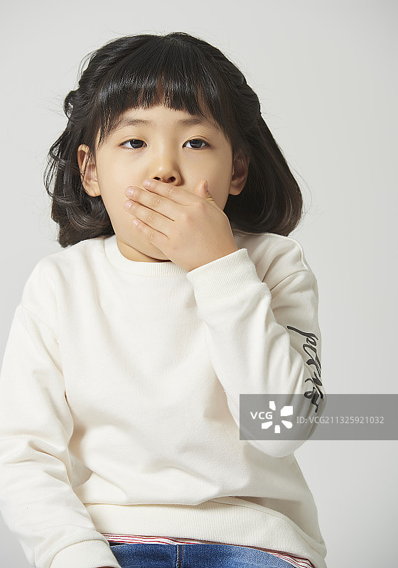 小女孩咳嗽，用手捂住嘴，灰色背景图片素材