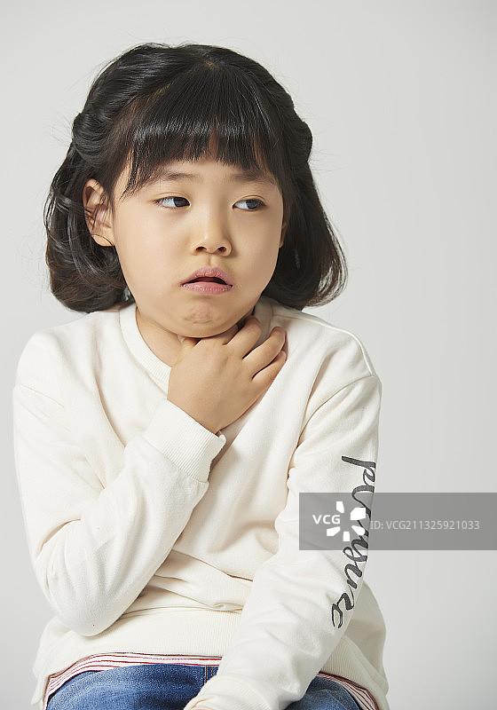 灰色背景上手捂喉咙咳嗽的小女孩图片素材