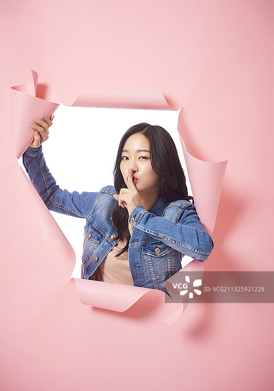 女人站在粉色墙纸的洞后微笑图片素材