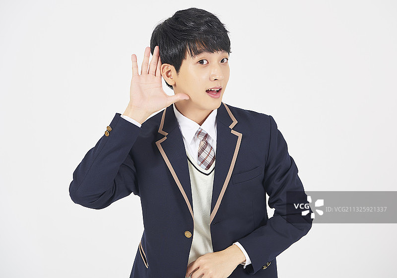 少年穿着制服，双臂交叉，在白色背景上微笑图片素材