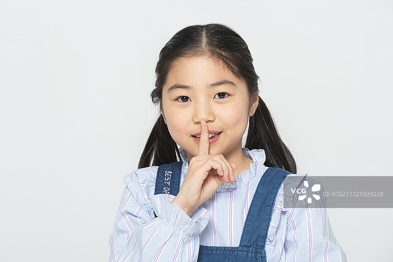 在白色背景上做出安静手势的小学女生图片素材