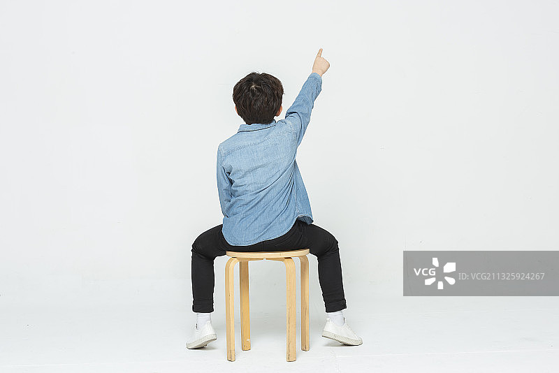 男孩坐在椅子上，手指向上方图片素材
