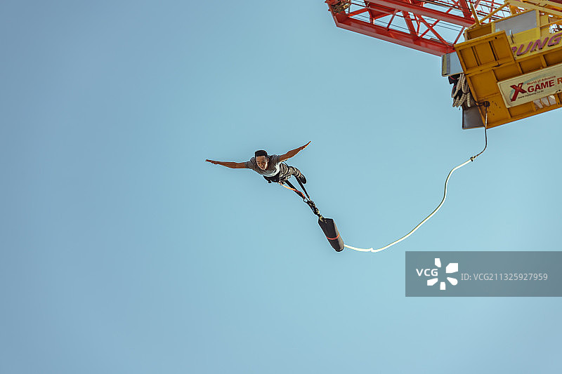 穿着安全带、手臂伸开在蹦极的男人，天空背景图片素材