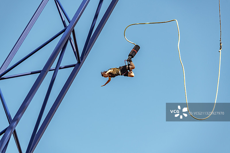 女子张开双臂蹦极跳，低角度拍摄图片素材